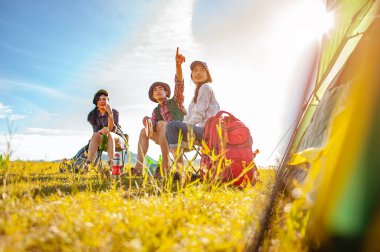Asyalı dağcı takımı sonbahar sezonunda orman yolunda kurulmuş bir çadırdan sonra oturup bir içkinin tadını çıkarıyorlar. Yürüyüş, yürüyüş, takım, orman, kamp, aktivite konsepti.