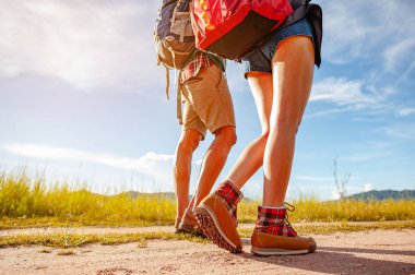 Geniş bir tarlada yaşayan Asyalı genç bir çift ormanı keşfetmek için sonbahar mevsiminde orman yolunda bir tatil aktivitesi olarak yürüyor. Yürüyüş, yürüyüş, takım, orman, kamp, aktivite konsepti.