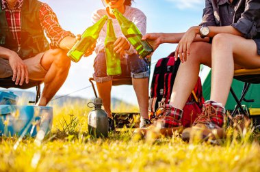 Asyalı dağcı takımı sonbahar sezonunda orman yolunda kurulmuş bir çadırdan sonra oturup bir içkinin tadını çıkarıyorlar. Yürüyüş, yürüyüş, takım, orman, kamp, aktivite konsepti.