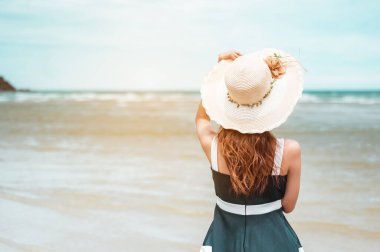 Şapkalı mutlu Asyalı kadınlar rüzgârla karşılaşıp kumsal tatilinde hayatın tadını çıkarıyorlar. Plaj, yaz, kaldırma stili, pozitif ruh hali, seyahat, rahatlama konsepti.