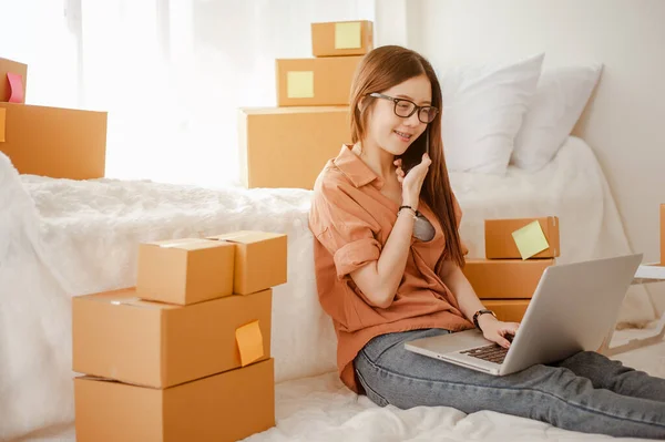 Young woman asian work from home talking with customers to sell products online and delivery for customer. Business owner, SME, shipping, work from home(WFH), freelance, Start up concept.
