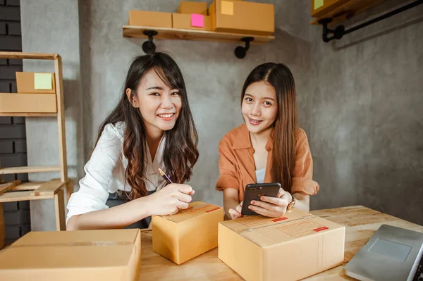 Young woman asian work from home talking with customers to sell products online and delivery for customer. Business owner, SME, shipping, work from home(WFH), freelance, Start up concept.