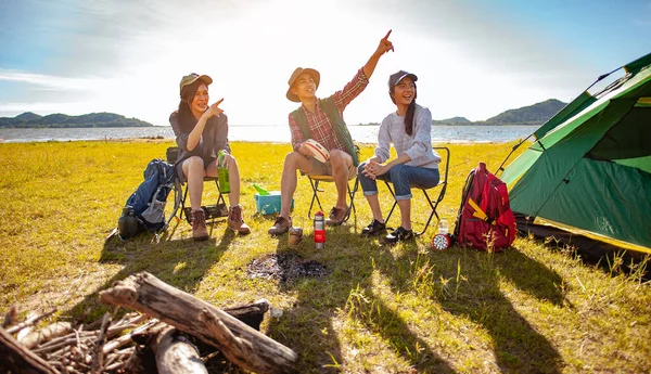 Team of asian climbers hiker are sitting and enjoying a drink after a set up outdoor tent in the forest path autumn season. Hiking, hiker, team, forest, camping , activity concept.