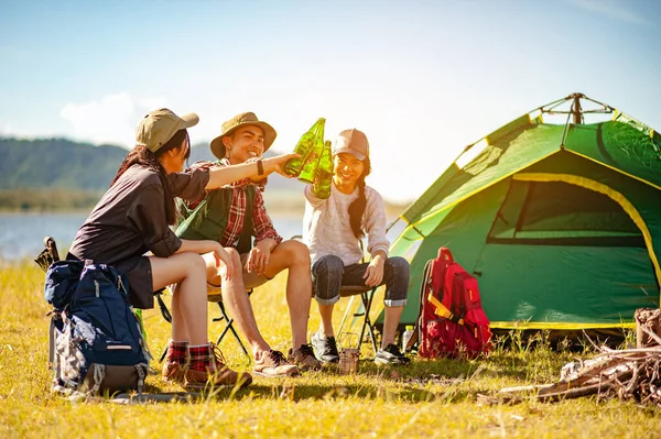 Team of asian climbers hiker are sitting and enjoying a drink after a set up outdoor tent in the forest path autumn season. Hiking, hiker, team, forest, camping , activity concept.