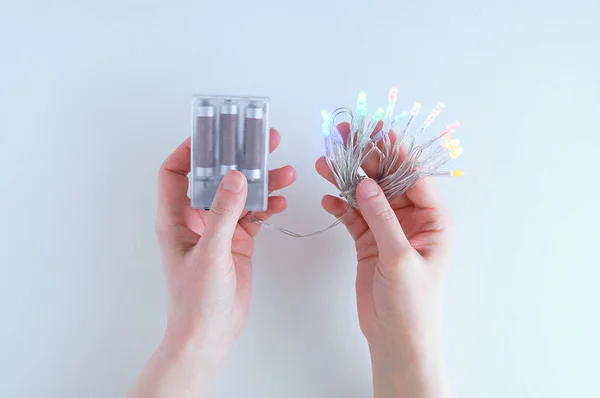 Veelkleurige Bloemenslingers Met Een Batterij Handen Van Een Blank Meisje — Stockfoto
