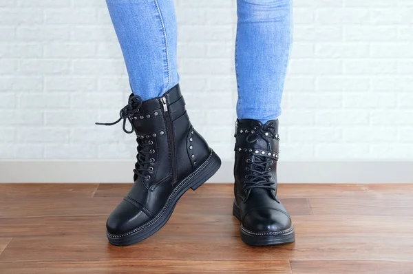 Mavi kotlu ve siyah ayakkabılı bir kızın bacakları. Beyaz bir duvarın arkasında.