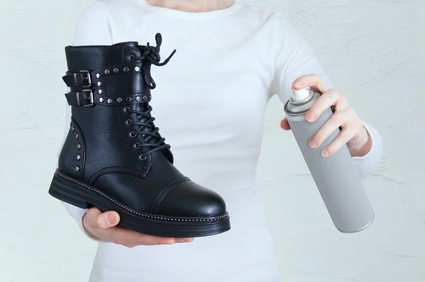 Leather shoe care. Black shoe and water-repellent spray for shoes in the hands of a Caucasian woman.
