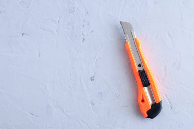 Construction yellow knife with a blade for home repair on a gray concrete background.