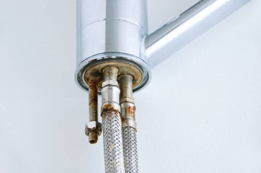 Beyaz arka plandaki su musluğunun ucundaki eski paslı boru..