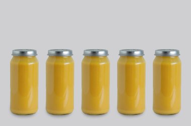 Gri arka planda cam bir kavanozda beş kutu konserve elma püresi..