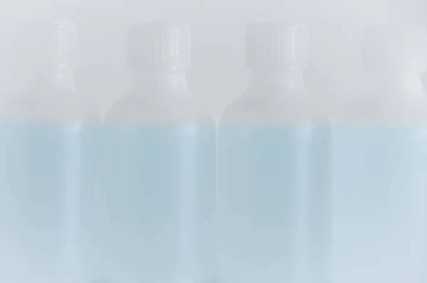 Cztery Białe Plastikowe Butelki Środkiem Dezynfekującym Niewyraźne Białe Tło — Zdjęcie stockowe