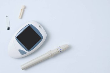Kan şekerini belirlemek için elektronik kan şekeri ölçer, neşter ve test şeridi. Beyaz arkaplan.