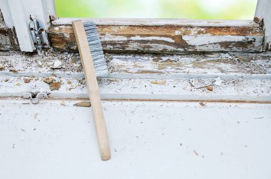 Camdaki eski boyayı silmek için metal kıllı fırça. Eski pencere.