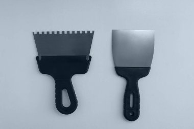 Beyaz arka planda duvarları çürütmek için kullanılan metal spatulalar..