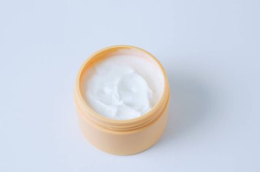 Beyaz arka planda sarı kavanozda beyaz yüz kremi. Yan görünüm