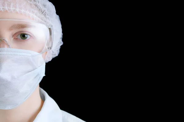 Female doctor full face in a protective mask and glasses on a black background.