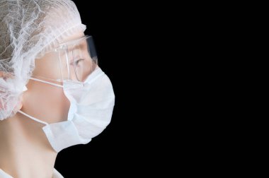 Beyaz kadın doktor profili koruyucu bir maske ve siyah bir arka planda gözlük takıyor..