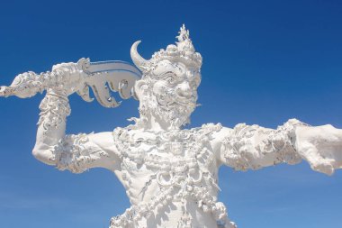 Wat Rong Khun 'un girişindeki Ölüm Meleği heykeli ya da Beyaz Tapınak, üzerinde cam parçaları gömülü..