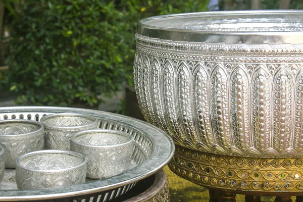 Traditionelle kleine thailändische Wasserschalen in einem silbernen Tablett, gesehen in Tempeln, um Wasser aus dem Inneren der größeren Schüssel zu gießen. — Stockfoto