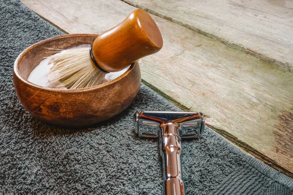 Shiny safety razor, shaving brush and lather in bowl. Old-school wet shaving in rustic wooden table, with copy space. Stock Image