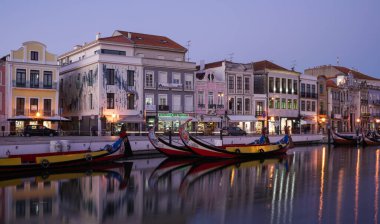 Aveiro Portugal - Mart 2019: Şehir merkezi Art Nouveau binaları ve Moliceiro tekneleri gün batımından sonra kanala yansıdı.