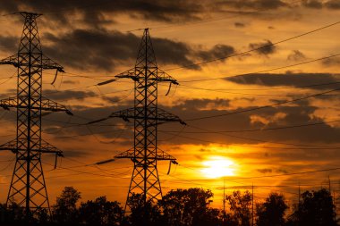 Batan güneşin elektrik hatları. Gökyüzüne karşı yüksek voltajlı kablolar. Moskova bölgesinde gün batımı.