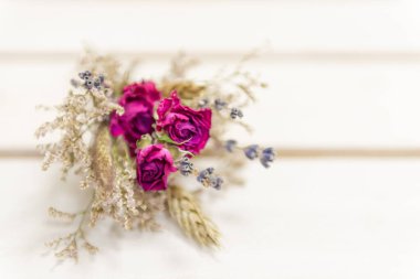 Küçük bir buket kurumuş çiçek. Güzelliği korumuş. Beyaz bir bankta küçük buketler.