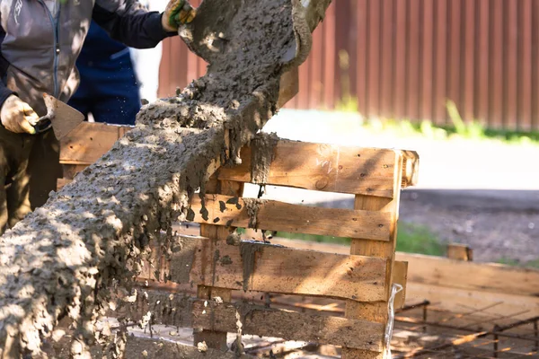 The concrete is poured on a wooden tray. As it merges down, the concrete splashes a lot of spray.