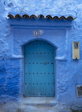 Tipik, eski, karmaşık bir şekilde oyulmuş, çivili, Fas Riad kapısı, kapı çerçevesi ve eski ev. Medine 'deki mavi şehrin güzel manzarası. CHEFCHAOUEN, FOCCO 'da boyalı evler