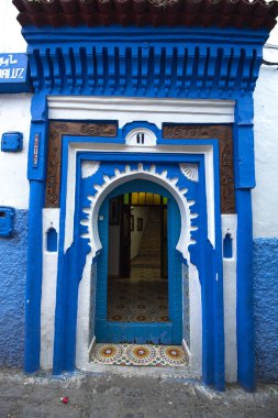 Tipik, eski, karmaşık bir şekilde oyulmuş, çivili, Fas Riad kapısı, kapı çerçevesi ve eski ev. Medine 'deki mavi şehrin güzel manzarası. CHEFCHAOUEN, FOCCO 'da boyalı evler