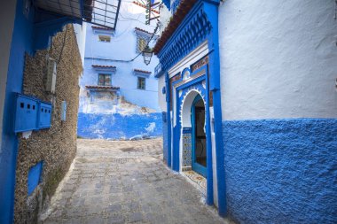 Mavi şehrin güzel manzarası CheFCHAOUEN, Medina 'daki MoroCCO. Geleneksel Fas mimari detayları ve boyalı evler. Kapısı olan bir sokak ve kemerli parlak mavi duvarlar