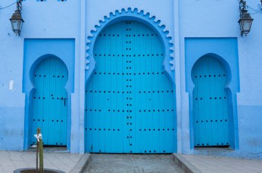 Tipik, eski, karmaşık bir şekilde oyulmuş, çivili, Fas Riad kapısı, kapı çerçevesi ve eski ev. Medine 'deki mavi şehrin güzel manzarası. CHEFCHAOUEN, FOCCO 'da boyalı evler