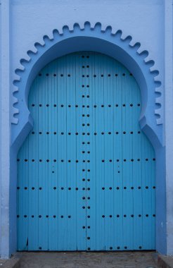 Tipik, eski, karmaşık bir şekilde oyulmuş, çivili, Fas Riad kapısı, kapı çerçevesi ve eski ev. Medine 'deki mavi şehrin güzel manzarası. CHEFCHAOUEN, FOCCO 'da boyalı evler