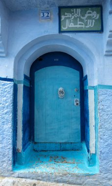 Tipik, eski, karmaşık bir şekilde oyulmuş, çivili, Fas Riad kapısı, kapı çerçevesi ve eski ev. Medine 'deki mavi şehrin güzel manzarası. CHEFCHAOUEN, FOCCO 'da boyalı evler