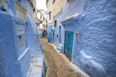 Mavi şehrin güzel manzarası CheFCHAOUEN, Medina 'daki MoroCCO. Geleneksel Fas mimari detayları ve boyalı evler. Kapısı olan bir sokak ve kemerli parlak mavi duvarlar