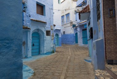 Medine 'deki mavi şehrin güzel manzarası. Geleneksel Fas mimari detayları ve boyalı evler. Kapısı ve parlak mavi duvarları olan sokak Chefchaouen, Fas