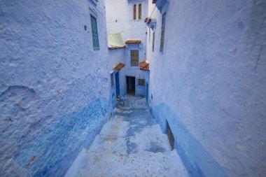 Medine 'deki mavi şehrin güzel manzarası. Geleneksel Fas mimari detayları ve boyalı evler. Kapısı ve parlak mavi duvarları olan sokak Chefchaouen, Fas