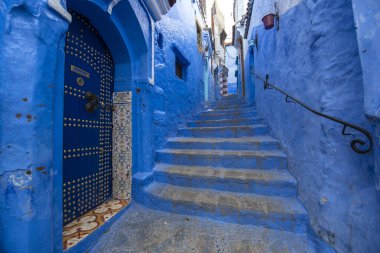 Medine 'deki mavi şehrin güzel manzarası. Geleneksel Fas mimari detayları ve boyalı evler. Kapısı ve parlak mavi duvarları olan sokak Chefchaouen, Fas