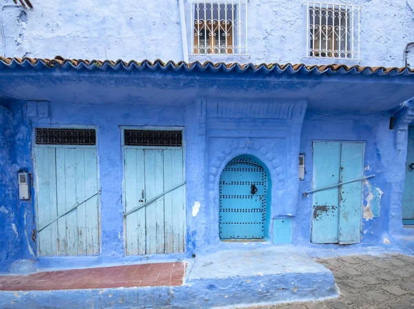 Beautiful view of the blue city in the medina. Traditional moroccan architectural details and painted houses.  street with door and bright blue walls with arch in CHEFCHAOUEN, MOROCCO