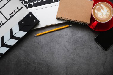 Ofis malzemeleri, film, dizüstü bilgisayar, akıllı telefon, tablet, kahve fincanı, kalem, not defteri ve ahşap masa manzaralı fotoğraf..