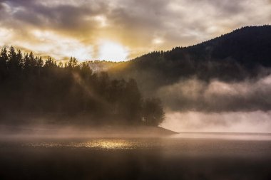 Kışın Kruth-Wildenstein Gölü 'nde güzel sisli bir gün batımı, Vosges, Fransa.