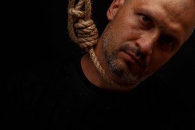 Karanlık bir arka plan üzerinde boynunda ilmik olan intihara meyilli adam