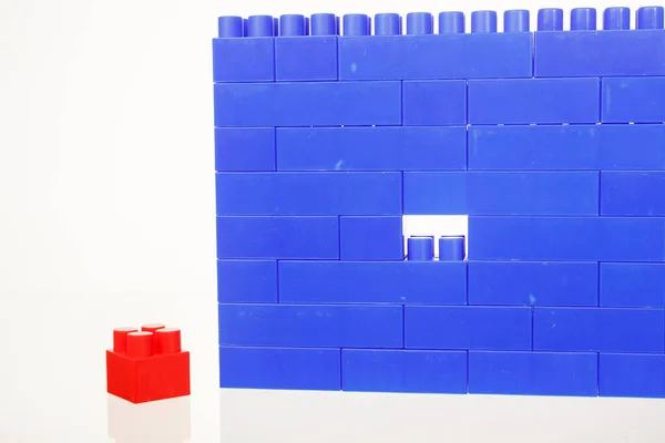 Una pared de ladrillos de juguetes de construcción de plástico de colores azules para niños, con una pieza faltante —  Fotos de Stock