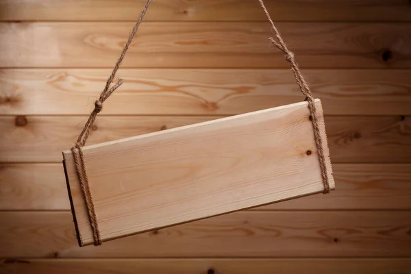 Houten uithangbord op een ruw touw op een mooie houten achtergrond — Stockfoto