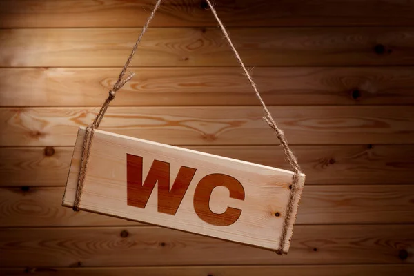 Letrero de madera con las palabras WC en una cuerda áspera sobre un hermoso fondo de madera —  Fotos de Stock