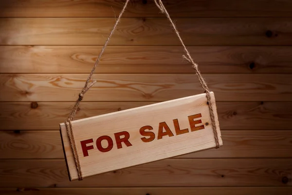 Wooden signboard with the words FOR SALE on a rough rope on a beautiful wooden background — Stock Photo, Image