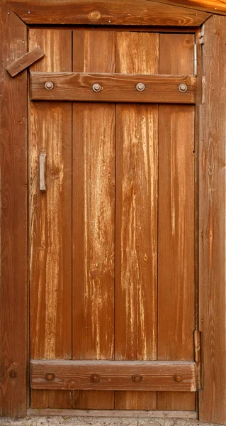 Old dirty shabby wooden door covered in brown paint. With a handle and constipation inserted into a wall of white silicate brick. — Stock Photo, Image