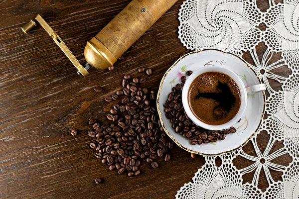 Kahve fincanı ve kahve çekirdekleri ahşap masa manzaralı.