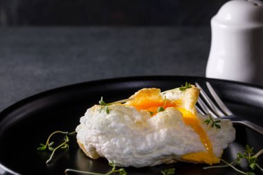 Siyah tabakta Orsini yumurtası ve koyu arkaplanda tere salatası.