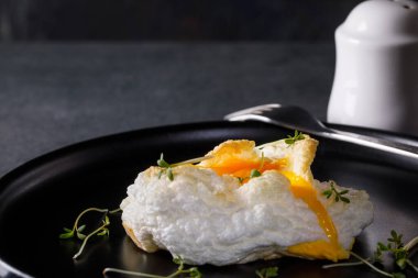 Siyah tabakta Orsini yumurtası ve koyu arkaplanda tere salatası.